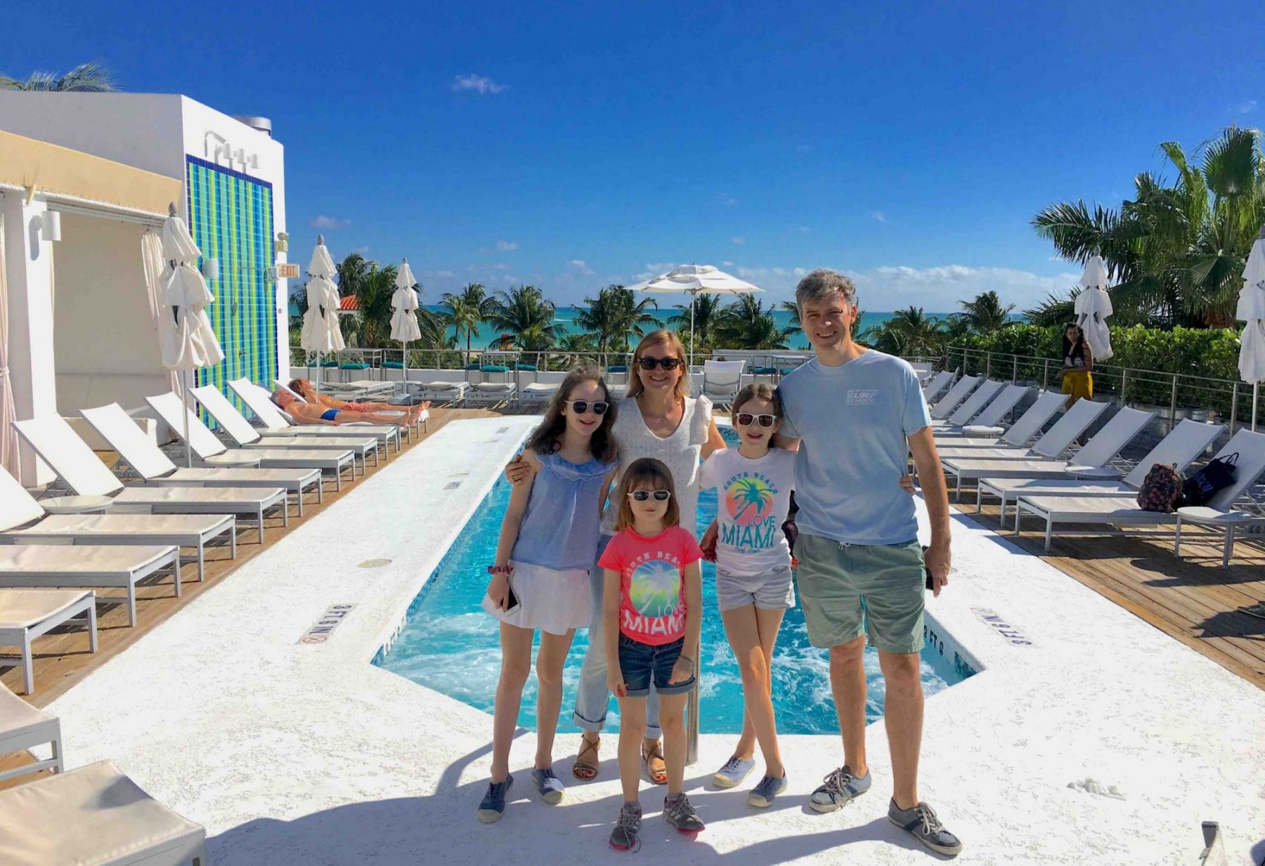 Family poing in front of a rooftop pool in South Beach during an Offbeat Miami Art Deco tour.