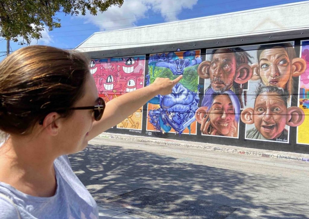 Our tour guide and manager Heloise on an offbeat miami street art tour in Wynwood, showing a detail on a mural.